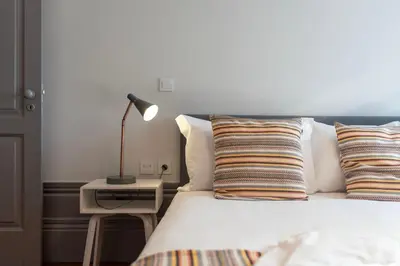a bed with pillows and a lamp on a side table at Cedofeita's Blue House in Porto