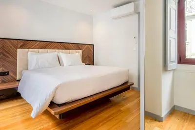 a bedroom with a white bed with a wooden headboard at Almada 505 City Center Duplex in Porto