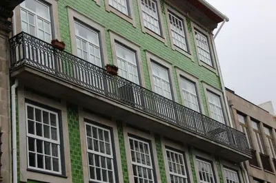 a green building with white windows and a balcony at Flower 45 Suite @ Rua das Flores in Porto