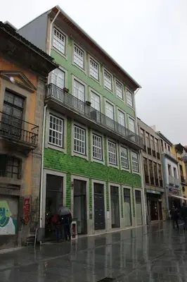 a green building on a city street in the rain at Flower 45 Suite @ Rua das Flores in Porto