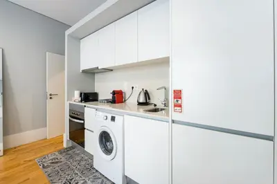 a white kitchen with a washer and dryer at GuestReady - Comfortable Retreat in Porto in Porto