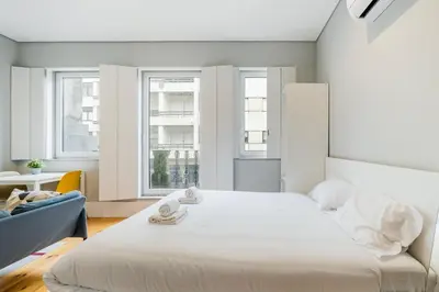 a bedroom with a large white bed and two windows at GuestReady - Comfortable Retreat in Porto in Porto