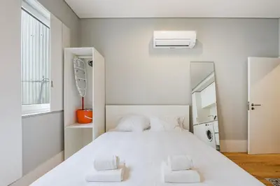 a white bedroom with a large white bed with two pillows at GuestReady - Comfortable Retreat in Porto in Porto