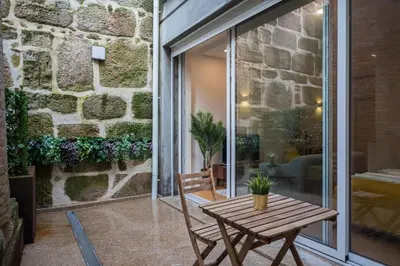 a patio with a wooden table and a stone wall at Golden Factory Apartment Downtown, Terrace and AC in Porto