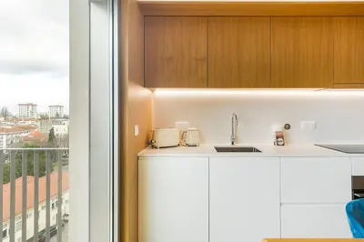 a kitchen with white cabinets and a window at GuestReady - Central Park in Porto in Porto