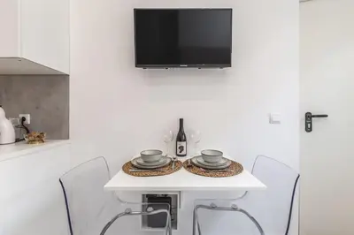 a white table with chairs and a tv on a wall at Studio de luxo no Porto - T0 in Porto