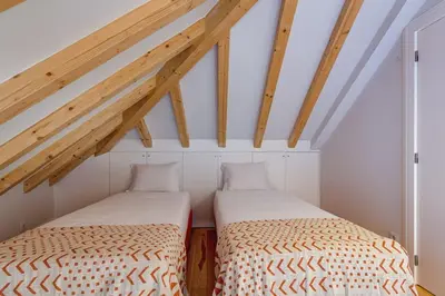 two beds in a attic room with wooden beams at Cais das Pedras Duplex by Cozy Stay in Porto