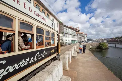a train on a bridge over a river with people on it at Cais das Pedras Duplex by Cozy Stay in Porto