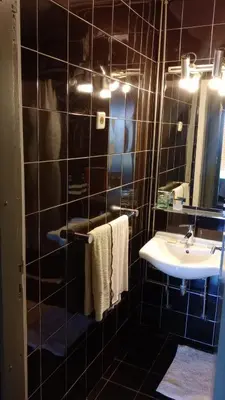 a black tiled bathroom with a sink and a mirror at Praceta in Porto