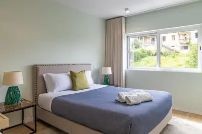 a bedroom with a bed with a blue blanket and a window at Lu's Douro View Apartment in Vila Nova de Gaia