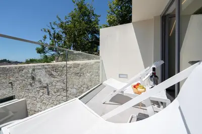 a balcony with white furniture and a stone wall at Host Wise - Fervença Boutique Palace in Vila Nova de Gaia