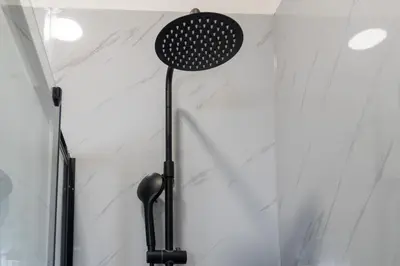 a shower head in a bathroom with white marble walls at Maison d'Angelina: in the heart of Porto in Porto