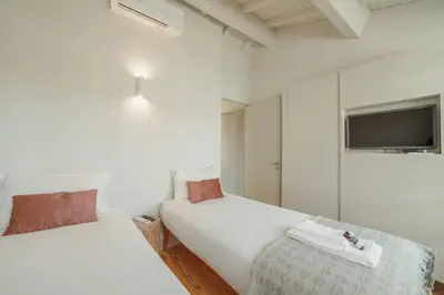 a bedroom with two beds and a tv on the wall at Deluxe Duplex by Hosty in Porto