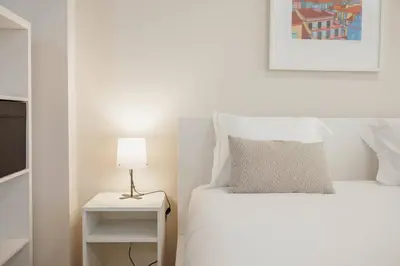 a white bedroom with a bed and a lamp at Trindade Deluxe by Hosty in Porto