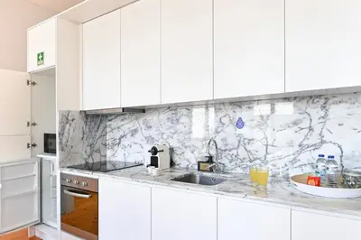 a kitchen with white cabinets and marble counter tops at Oporto Sunset Blue Balcony in Porto