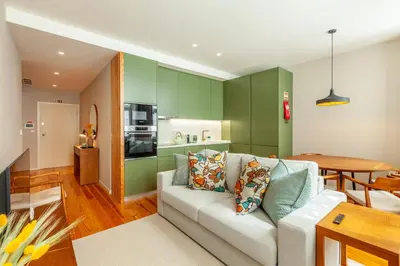 a living room with a white couch and a kitchen at Savvy Signature Apartments in Porto