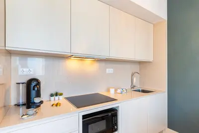 a kitchen with white cabinets and a sink at Stylish Poveiros Flat w Balcony by LovelyStay in Porto