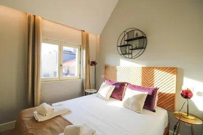 a bedroom with a large white bed with a window at Saudade do Porto in Porto