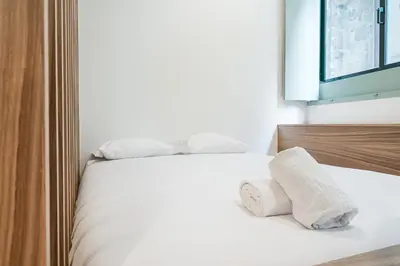 a white bed with two rolled towels on it at GuestReady - A modern stay in Downtown in Porto