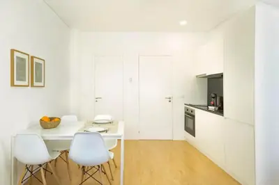 a white kitchen with a table and two white chairs at Fernandes Tomas Rooftop in Porto