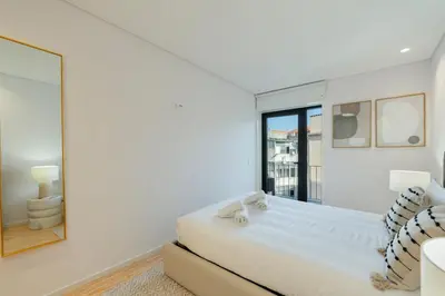 a white bedroom with a bed and a window at GuestReady - Comfortable stay in Porto in Porto