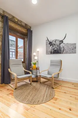 a living room with two chairs and a bull picture on the wall at Charming Studio with Garden in Porto in Porto