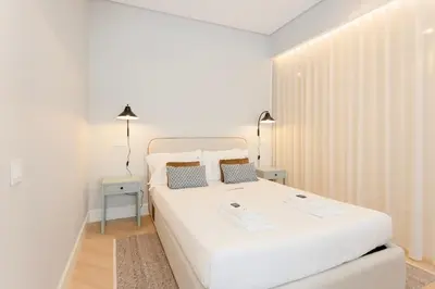 a white bedroom with a large white bed with two pillows at Liiiving in Porto - Luxury Design Apartments in Porto