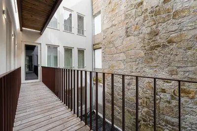 a balcony with a wooden walkway next to a stone wall at GuestReady - Little Johnny in Porto