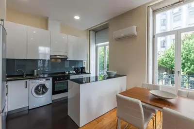 a kitchen with white cabinets and a wooden table at BO - Fernandes Tomás in Porto