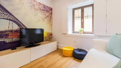a living room with a tv and a white couch at Porto River Flat w/ Patio by LovelyStay in Porto