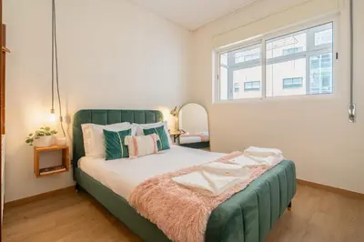 a bedroom with a green bed with a window at Jardim do Morro Apartment By Porto Stories in Vila Nova de Gaia