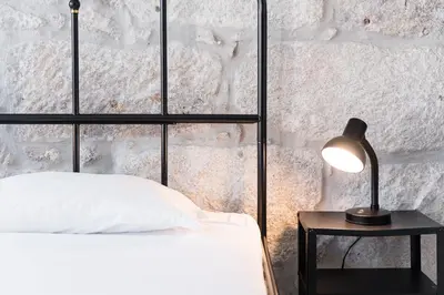 a bedroom with a bed and a lamp on a table at PortoNest Downtown Studios in Porto