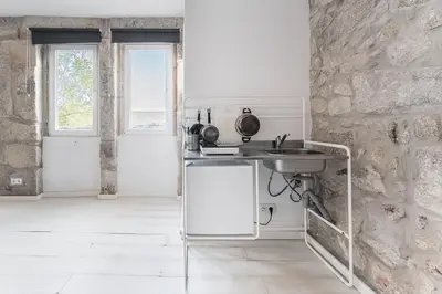a kitchen with a sink and a stone wall at PortoNest Downtown Studios in Porto