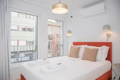 a bedroom with a large white bed with two windows at Liiiving in Porto - Modern & Glam Apartment M in Porto