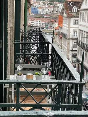 a table with two wine glasses on a balcony at São João Boutique Apartment in Porto