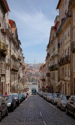 a cobblestone street with cars parked on the sides at São João Boutique Apartment in Porto