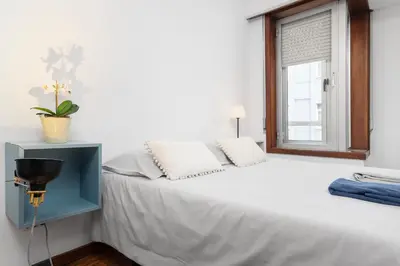 a bedroom with a large white bed with a window at Porto Cozy Space in Porto