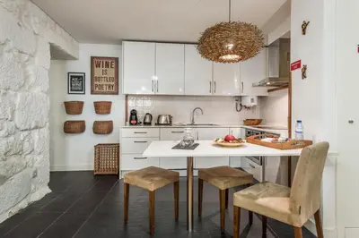 a kitchen with white cabinets and a table with chairs at Clérigos Design by Hosty in Porto