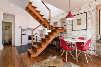 a kitchen and dining room with a wooden staircase and red chairs at Clérigos Design by Hosty in Porto