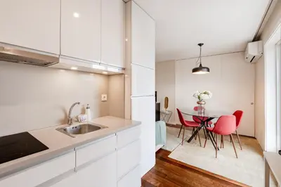 a kitchen with white cabinets and a table with red chairs at VIVA Peaceful Zen Retreat in Porto