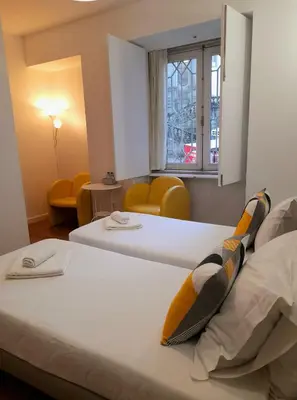 two beds in a hotel room with yellow chairs at Clérigos Ville Porto Rooms in Porto