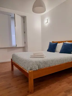 a bedroom with a wooden bed with blue pillows at Clérigos Ville Porto Rooms in Porto