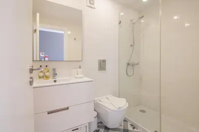 a white bathroom with a toilet and a shower at Central location with balcony & equipped kitchen in Porto