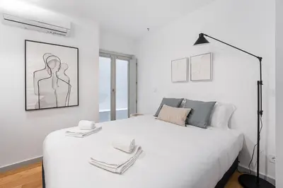 a white bedroom with a large white bed with towels on it at GuestReady - Downtown Refuge with Private Parking in Porto