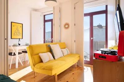 a yellow couch in a living room with a table at *Lighty Santa Catarina Studio* Balcony/Dishwasher in Porto