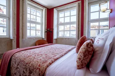 a bedroom with a bed with red walls and windows at Authentic Porto Suites in Porto