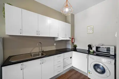 a white kitchen with a sink and a washing machine at Apartamento D' Alegria in Porto