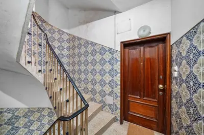 a staircase with blue and white tiles and a wooden door at Apartamento D' Alegria in Porto