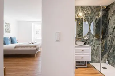 a white bedroom with a bed and a mirror at GuestReady - Relaxing moment in a vibrant city in Porto