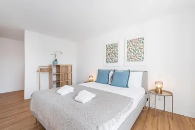 a white bedroom with a large bed with blue pillows at GuestReady - Relaxing moment in a vibrant city in Porto